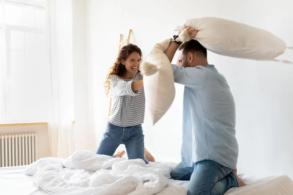 Glückliches junges Paar kämpft und lacht im Bett. — Stockfoto