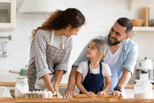 Moeder en vader onderwijzen kleine dochter om gebak te koken. — Stockfoto