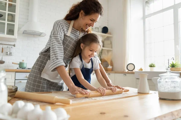 Madre insegnare piccola figlia a lavorare con mattarello. — Foto Stock