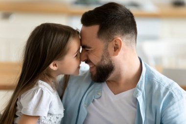 Close up young handsome father happily touch noses with daughter. clipart