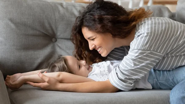 De cerca feliz madre acostada con la hija preescolar en el sofá . — Foto de Stock