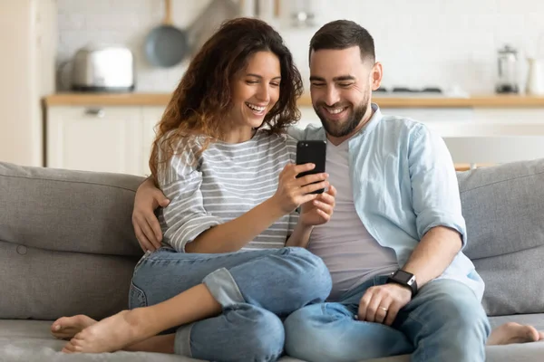 Крупным планом улыбающиеся мужчина и женщина обнимаются с помощью смартфона . — стоковое фото