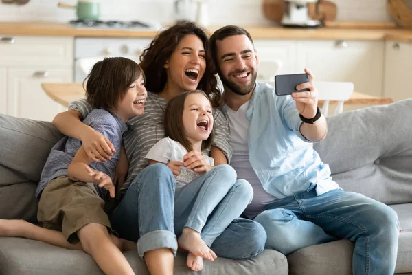 Закрыть счастливых родителей с маленькими детьми, использующих смартфон вместе . — стоковое фото