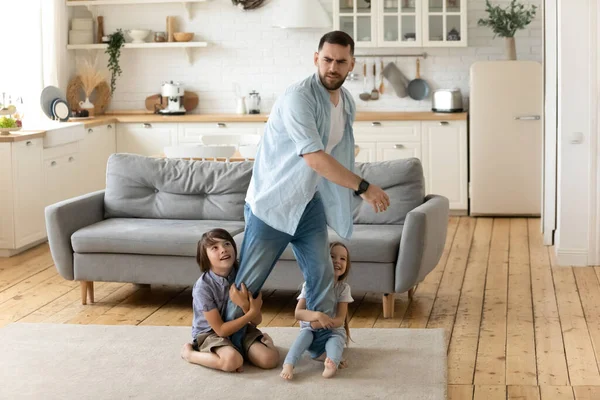 Hyperactive kids holding tired upset father legs. — Stock Photo, Image