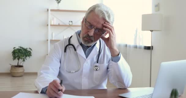 Médecin occupé sérieux écrivant prescription dans le bureau. — Video