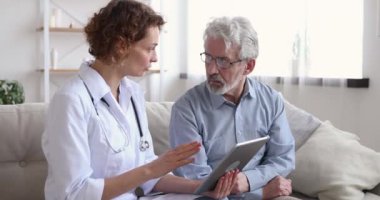Ciddi genç doktor yaşlı hastaya sağlık testi sonuçlarını gösteriyor.