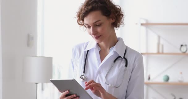 Χαμογελώντας νεαρή γυναίκα θεραπεύτρια χρησιμοποιώντας online εφαρμογή υγειονομικής περίθαλψης στο tablet. — Αρχείο Βίντεο