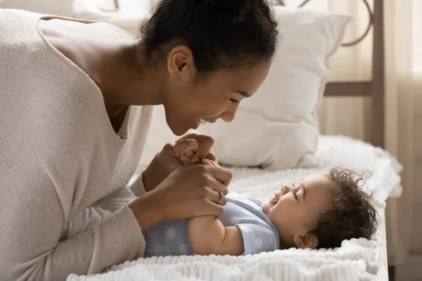 Sonriente madre afroamericana jugando con su pequeña hija en el dormitorio — Foto de Stock