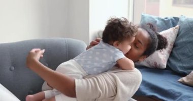 Rahat, genç, Afrikalı bir anne, tatlı bir bebekle oynuyor..