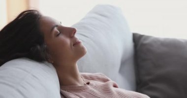 Serene genç ve çekici kadın rahat bir kanepede tek başına hayal kuruyor..