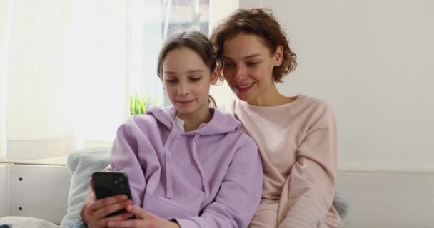 Glad tonåring flicka webb surfa media med mamma. — Stockvideo