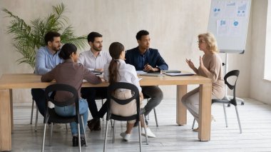 Orta yaşlı iş kadını takım lideri yönetim kurulunda bir toplantı düzenliyor.