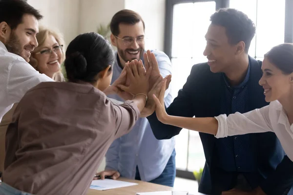 Heureux employés diversifiés joignant les mains, célébrer le succès du travail d'équipe à la réunion — Photo