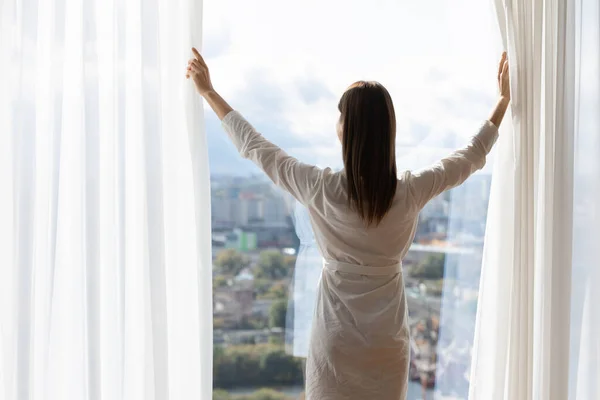 Indietro vista della donna tende aperte benvenuto nuovo giorno — Foto Stock