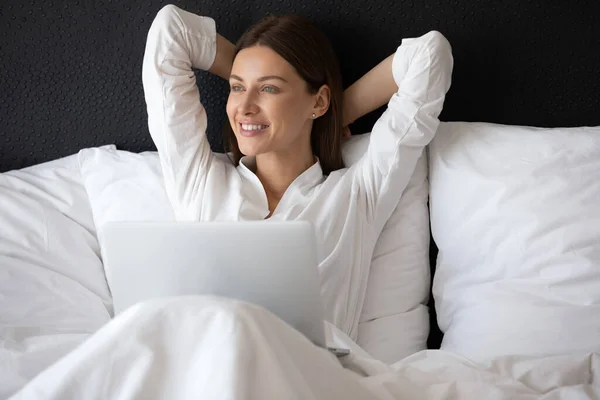 Mujer feliz soñando en la cama trabajando en la computadora — Foto de Stock