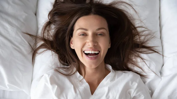 Gülümseyen genç bir kadının portresi rahat bir yatakta uyanıyor. — Stok fotoğraf