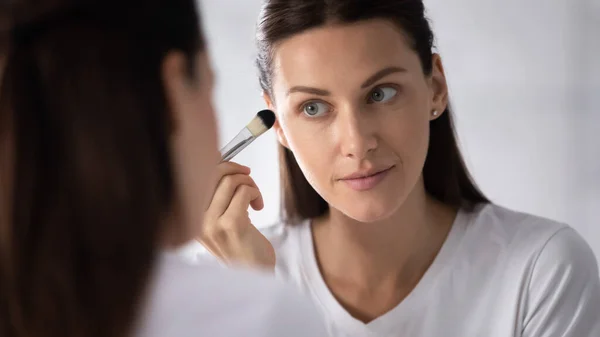 Mulher bonita olhar no espelho fazendo maquiagem — Fotografia de Stock