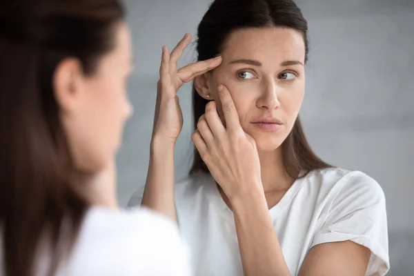 Anxious young woman look in mirror worried about face acne — Stock Photo, Image