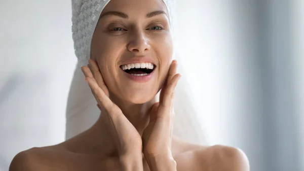 Smiling young woman do facial beauty procedures in bathroom