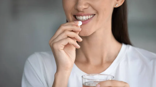 Smiling young woman take daily vitamins with water — Stock Photo, Image
