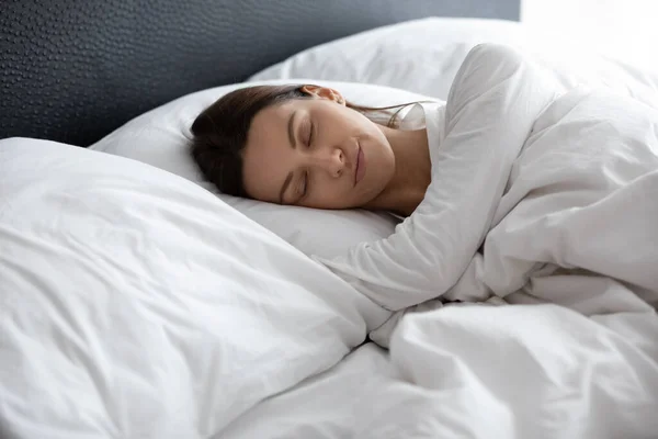 Молода жінка розслабляється спати в затишному ліжку вдома — стокове фото