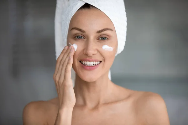 Giovane donna uso rivitalizzante crema viso in bagno — Foto Stock