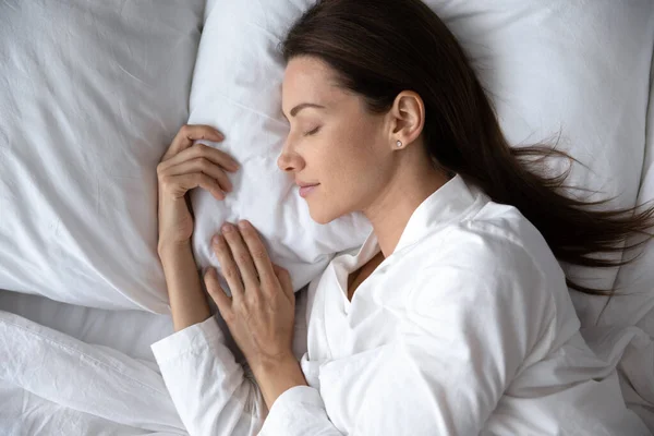 Bovenaanzicht van jonge vrouw slapen in wit gezellig bed — Stockfoto