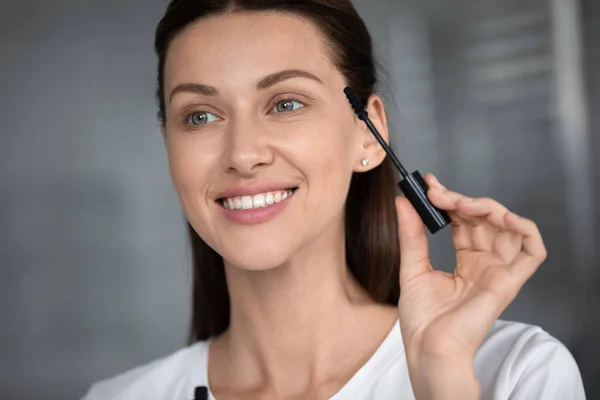 Lächelnde Frau bemalt Wimpern mit schwarzer Wimperntusche — Stockfoto