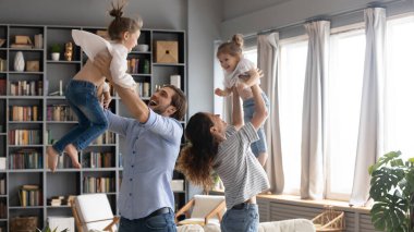 Mutlu ebeveynler iki küçük kızla eğlenceli aktif oyun oynuyorlar.