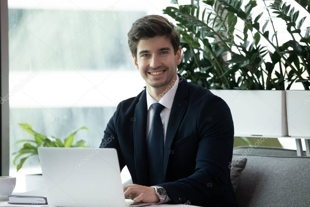 Happy businessman in formal wear using laptop and smiling