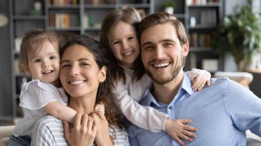 Kafadan çekilen mutlu genç anne ve baba ve kızları.