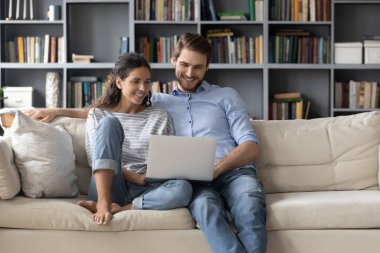 Gülümseyen kadın ve erkek kucaklaşır, dizüstü bilgisayar kullanır.