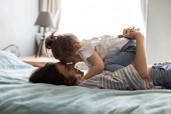 Happy loving mother and little daughter relaxing in bed together — Stock Photo, Image