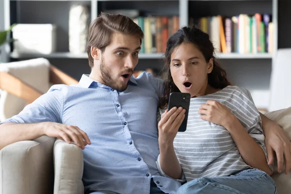 Шокированные молодой человек и женщина, глядя на экран телефона — стоковое фото