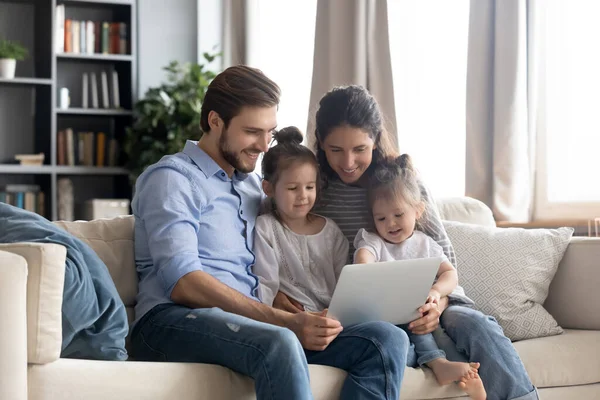 Jovem família feliz com duas filhas usando laptop juntas — Fotografia de Stock