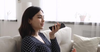 Akıllı telefon tutan güzel Asyalı kadın erkek arkadaşıyla hoparlör kullanıyor.