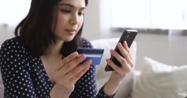 Vietnamlı kadın internet üzerinden kart ve cep telefonu kullanarak alışveriş yapıyor.