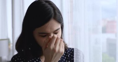 Vietnamlı genç bir kadın pencerenin yanında durmuş dışarı bakıyor ve bekliyor.