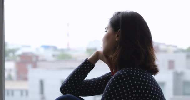 Triste asiático joven mujer sentado en la ventana alféizar se siente molesto — Vídeo de stock