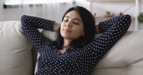 Kapalı Asyalı kadın ellerini başının arkasına koy ve kanepede dinlen. — Stok video