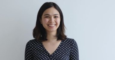 Asyalı kadın stüdyo arka planında kameraya bakıp gülümsüyor