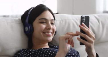 Yakın plan kaygısız Asyalı kadın kulaklıkla müzik dinliyor.