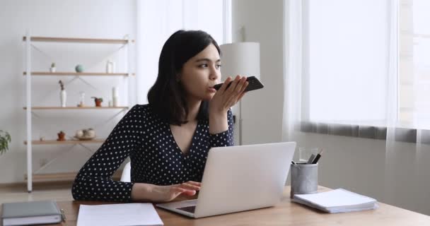 Aziatisch zakenvrouw zitten aan bureau spreekt met klant door speakerphone — Stockvideo