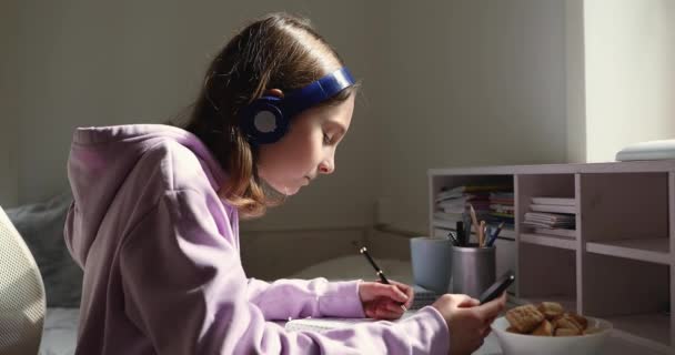 Chica adolescente concentrada usando auriculares, escuchando lección de audio . — Vídeo de stock