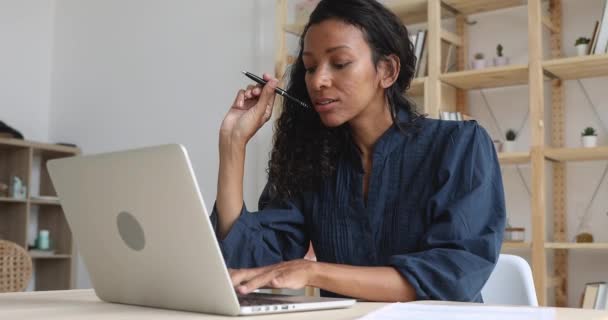 Sorrindo mulher de negócios africana trabalhando no laptop fazendo papelada na mesa — Vídeo de Stock