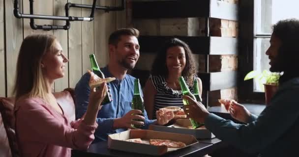Ευτυχισμένοι νέοι φίλοι που τρώνε πίτσα πίνοντας μπύρες χτυπώντας μπουκάλια — Αρχείο Βίντεο