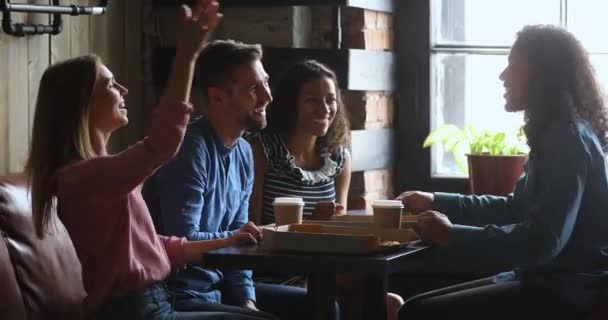 Счастливые мультирасовые студенты едят пиццу дают пять в кафе — стоковое видео