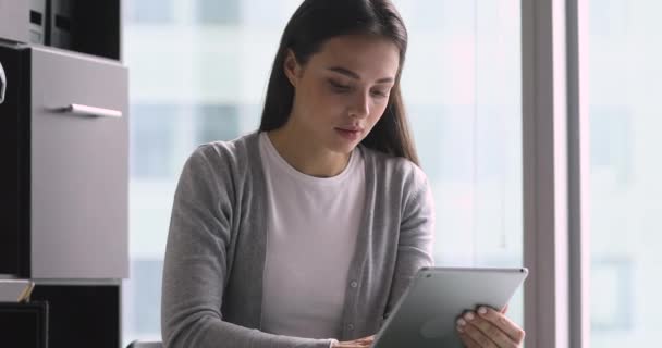 Fokuserad ung affärskvinna innehav med hjälp av digital tablett på kontoret — Stockvideo