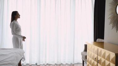 Mutlu kadın dantel perdeleri aç modern yatak odasında, ağır çekimde