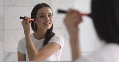 Elinde fırça tutan mutlu, genç bir kadın. Yüzüne allık sür.